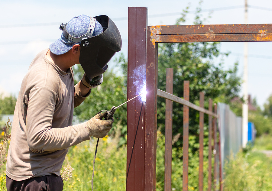 A worker welds metal for a fence